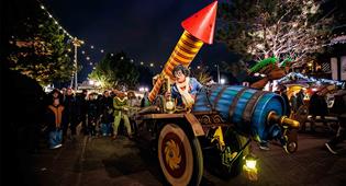 Efteling-karakters Max en Moritz zitten op een kleurrijke wagen met een grote vuurwerkpijl.